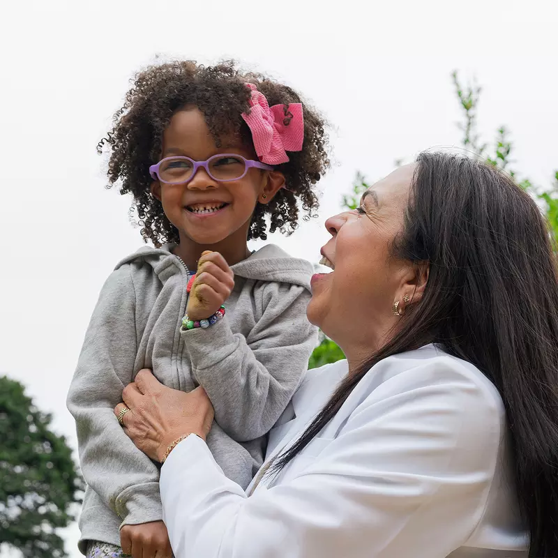 A Little Girl with Glasses is Carried by Her Physician Outside.