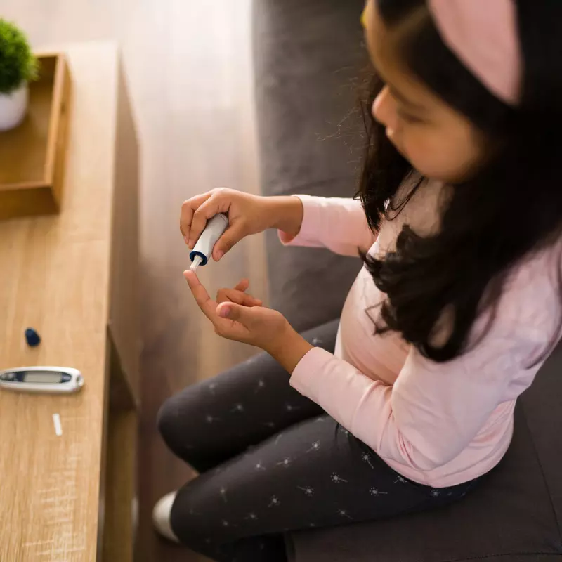 A little girl checking her sugar level using an at-home tester.