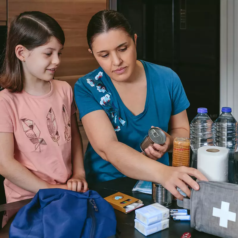 A Mother Looks Over a First Aid Kit with Her Daughter on the Kitchen Table.