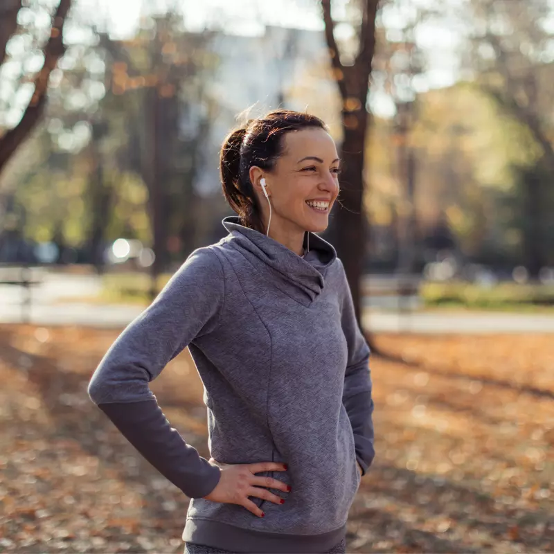 A Woman Smiles as She Takes a Break From a Jog in the Park