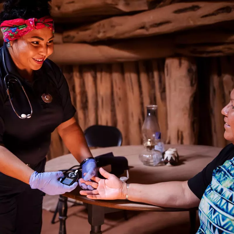 A Native American woman nurse that is about to do a test on a Native American patient.