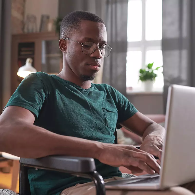 A Black Man Works on His Laptop at Home.