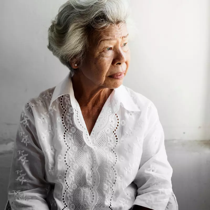 A Senior Woman Stares Out of a Window
