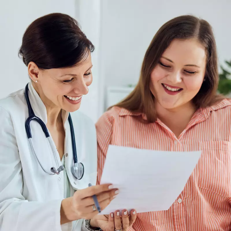 A Smiling Physician Goes Over a Chart with a Smiling Patient 
