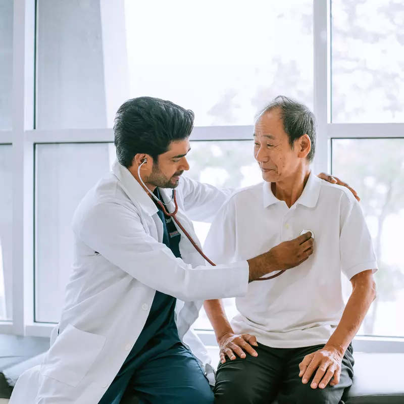 A Physician Listens to His Patients Heart with a Stethoscope 