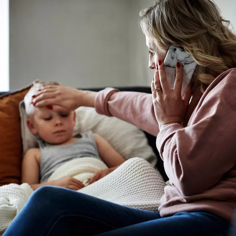 A Mother Checks Her Son's Temperature While on the Phone