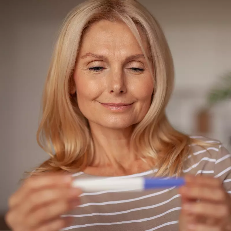 A Woman Smiles as She Looks at a Pregnancy Test