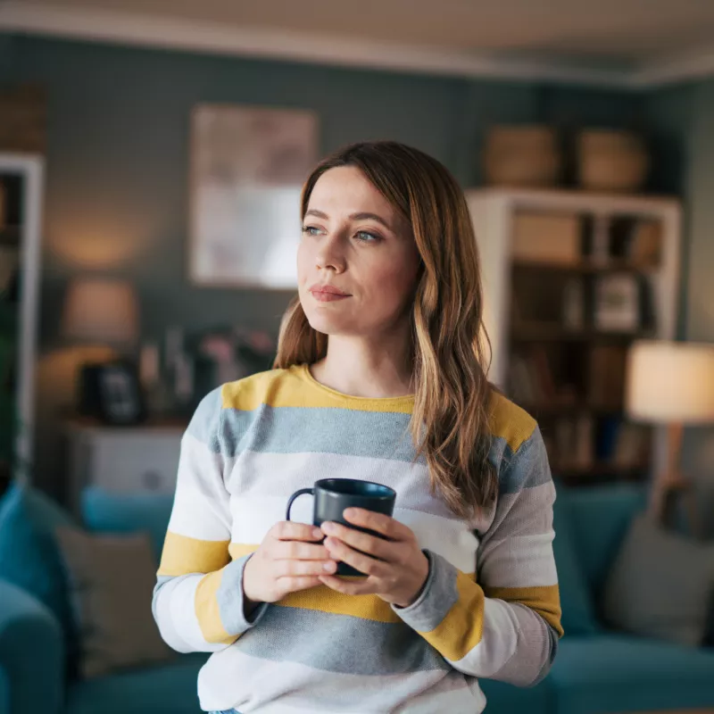 A Woman Looks Out Her Window While Drinking Coffee