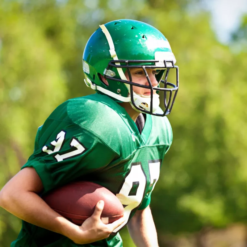 A Teen in Football Pads Getting Tackled