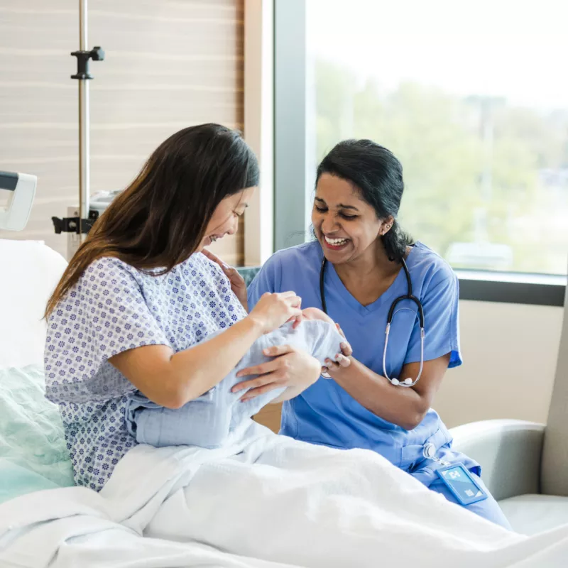 A Patient and a Nurse Laugh and Smile at Her Newborn Baby