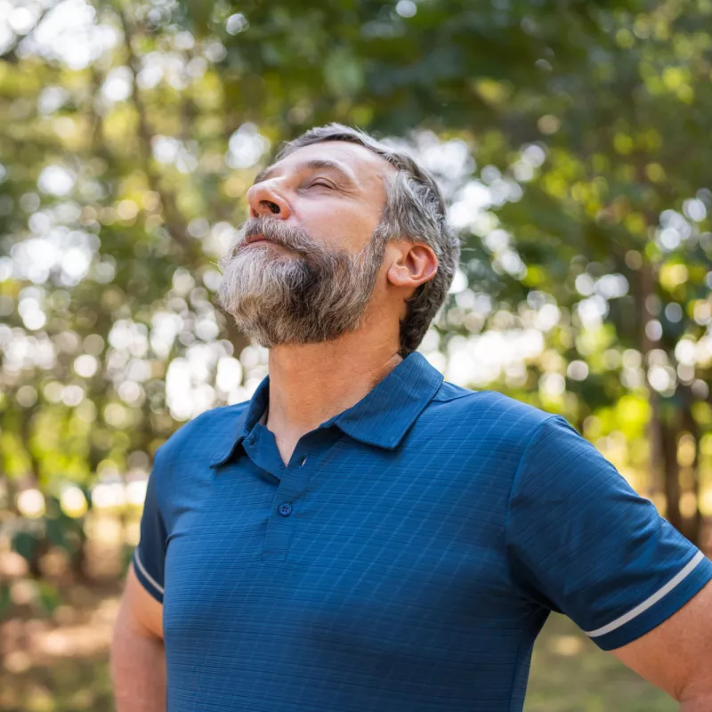 A Man Takes a Deep Breath Outdoors in the Woods