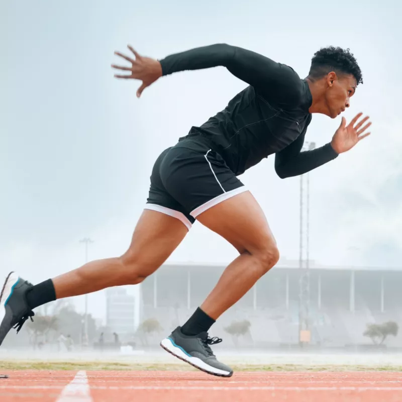 A Male Athlete Jumps Out of the Starting Blocks on a Track