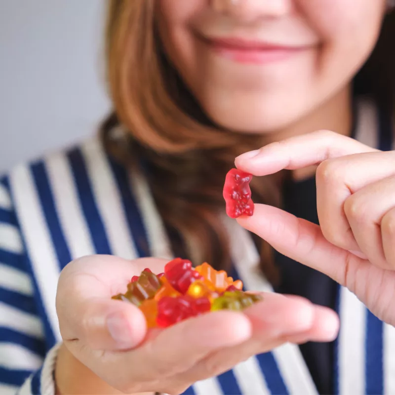 A Woman Smiles as She Selects a Gummy Bear Vitamin