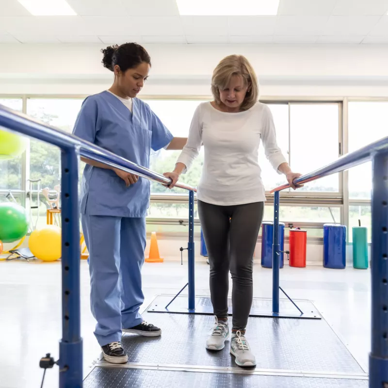 A Female Patient Attends Physical Therapy for Walking with a Therapist