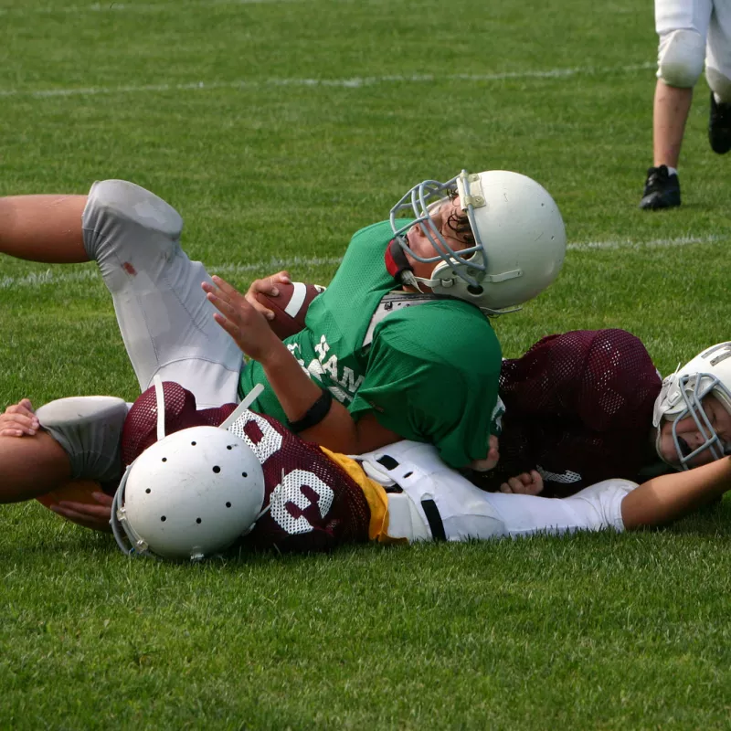 A Teen in Football Pads Getting Tackled