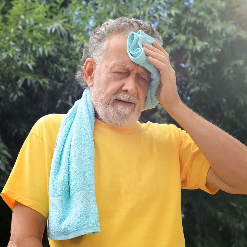 A Senior Wipes His Forehead While Out in the Hot Summer Sun 