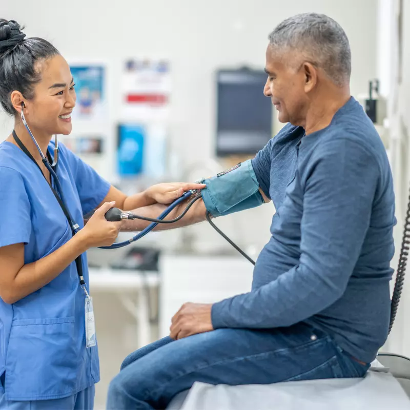 A Nurse Smiles as she Takes a Patient's Blood Pressure Readings.