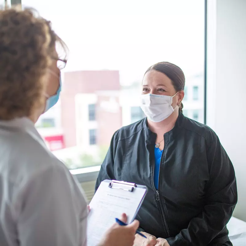 Patient speaking to her doctor, both wearing masks