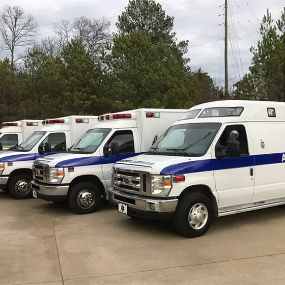 Four medical transport vans with the words Amtran sit in a parking lot