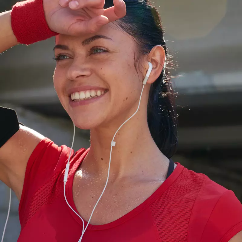 A woman with headphones in, dries off her forehead post workout.