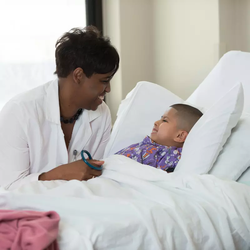 A physician speaks kindly to her young child patient.