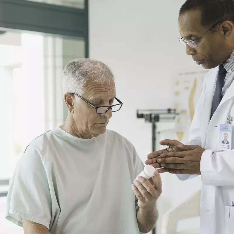 A male African American doctor discusses medication with a male Caucasian patient.