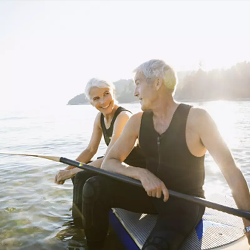 An older Caucasian couple takes the paddleboard on the lake.