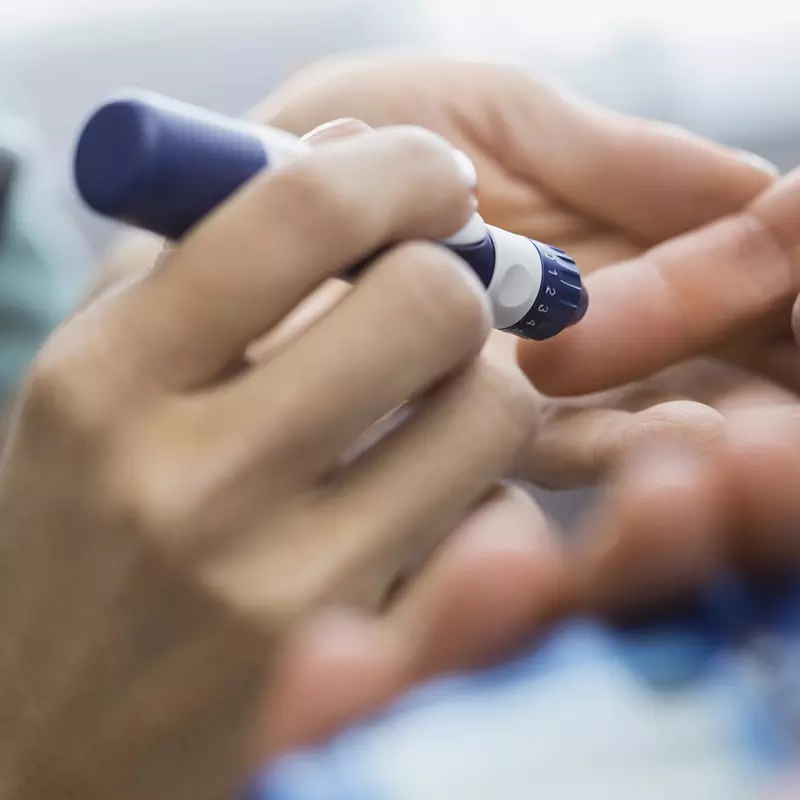 A diabetic patient takes a finger prick reading from an insulin pen.