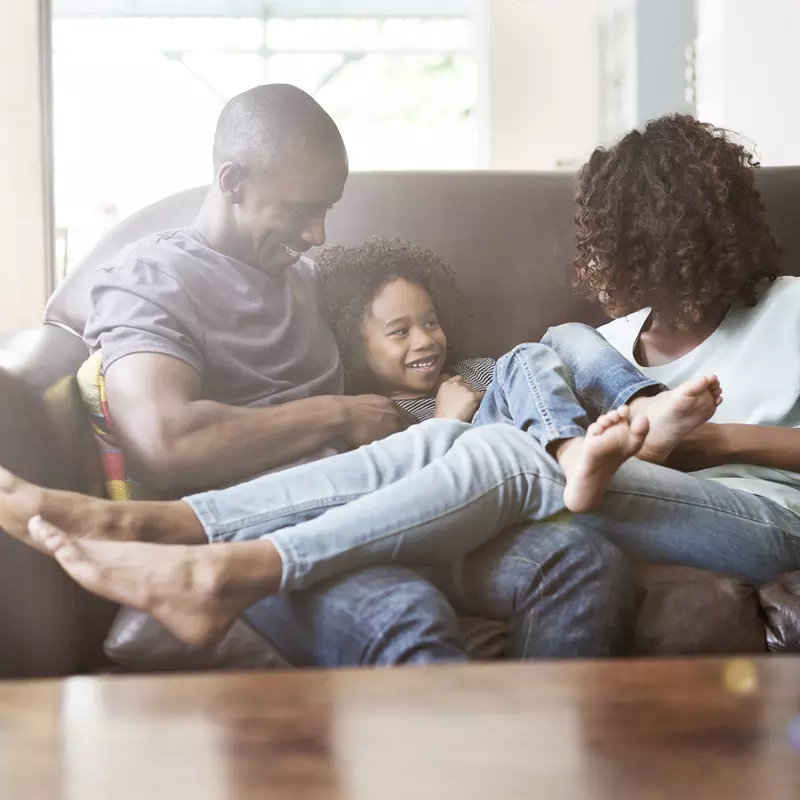 An African American family hangs out on the couch at home.