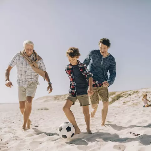 A family plays soccer on the beach.