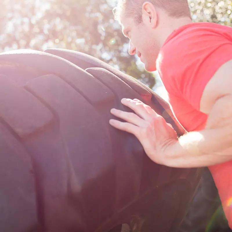 Man doing crossfit and pushing a tire.
