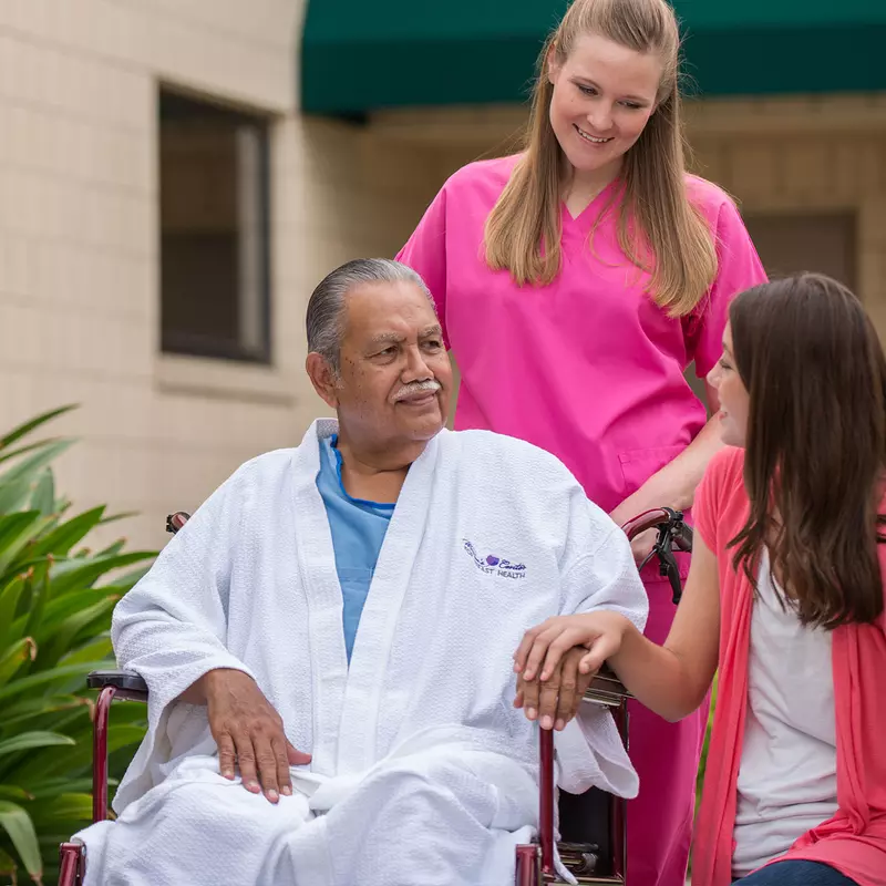 Elderly man in a wheelchair with his daughter and a hospice nurse.