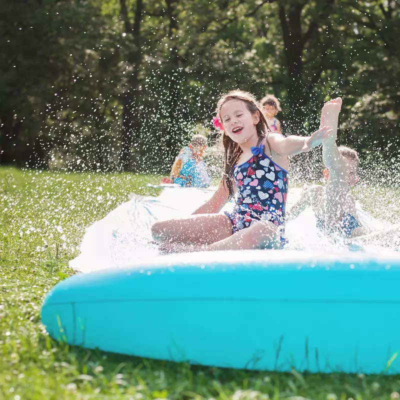 Happy children play on a slip and slide outside on a sunny day.