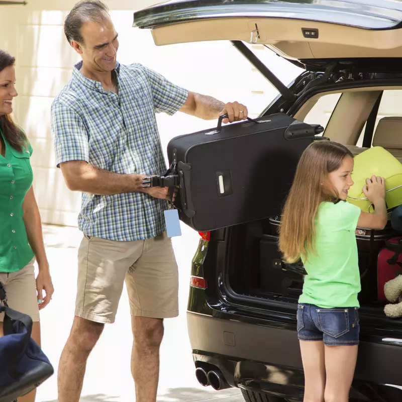 A family packs their car full of luggage.