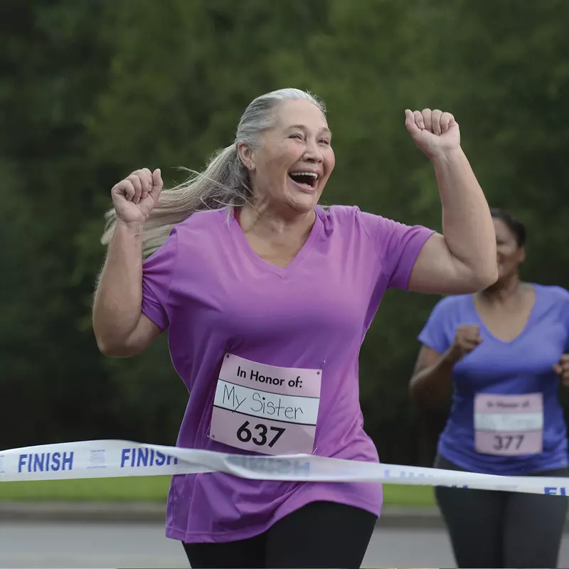 An older woman is ecstatic as she crosses the finish line of a charity foot race