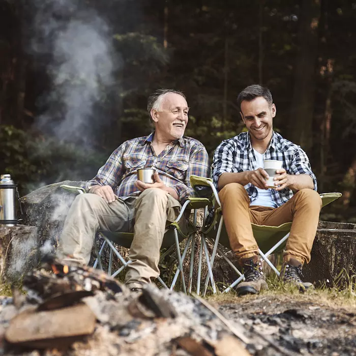 Two men sit in front of a fire and talk about their health
