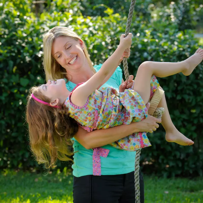A mom helps her daughter swing. 