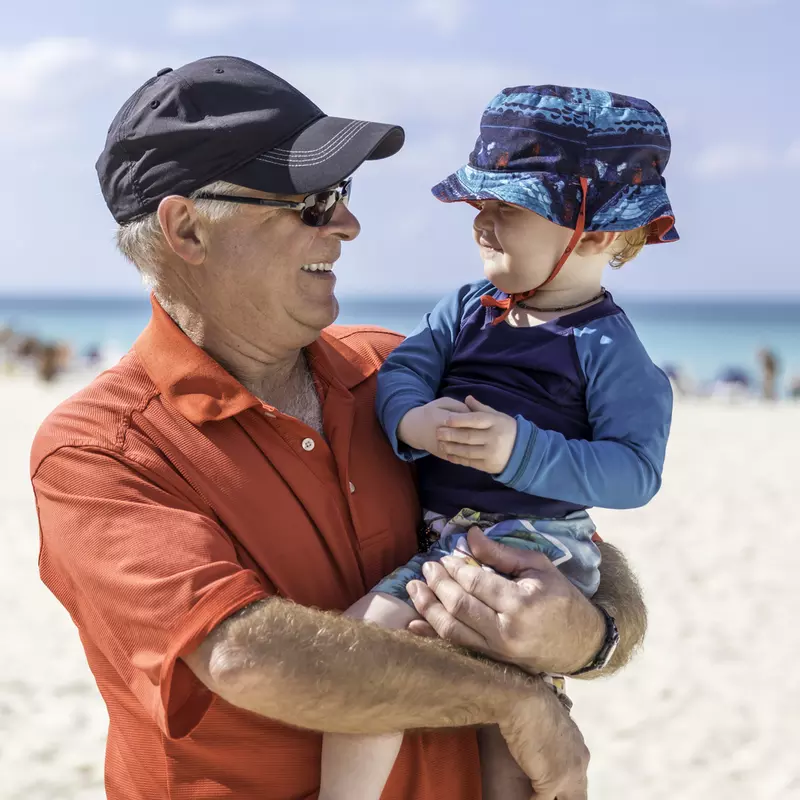 A grandfather and grandson practice sun safety at the beach.