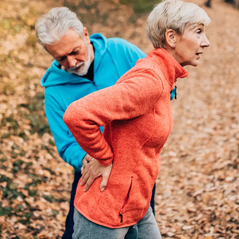 A woman experiences lower back pain during a run.