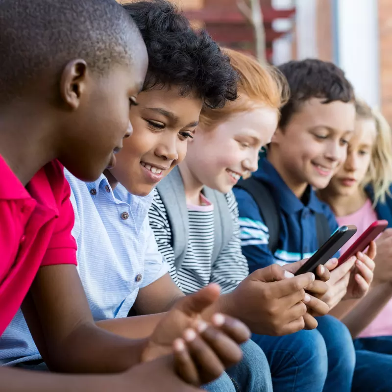 A group of kids use cell phones after school.