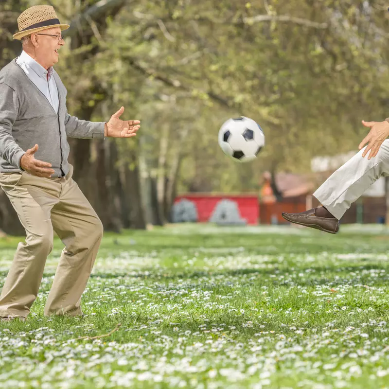 Seniors playing soccer in a park