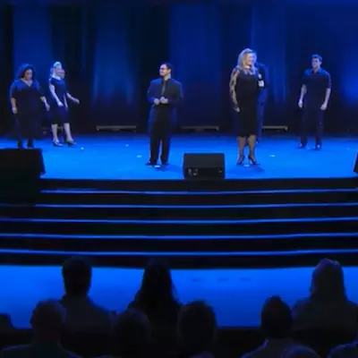 Group of men and woman singing on stage