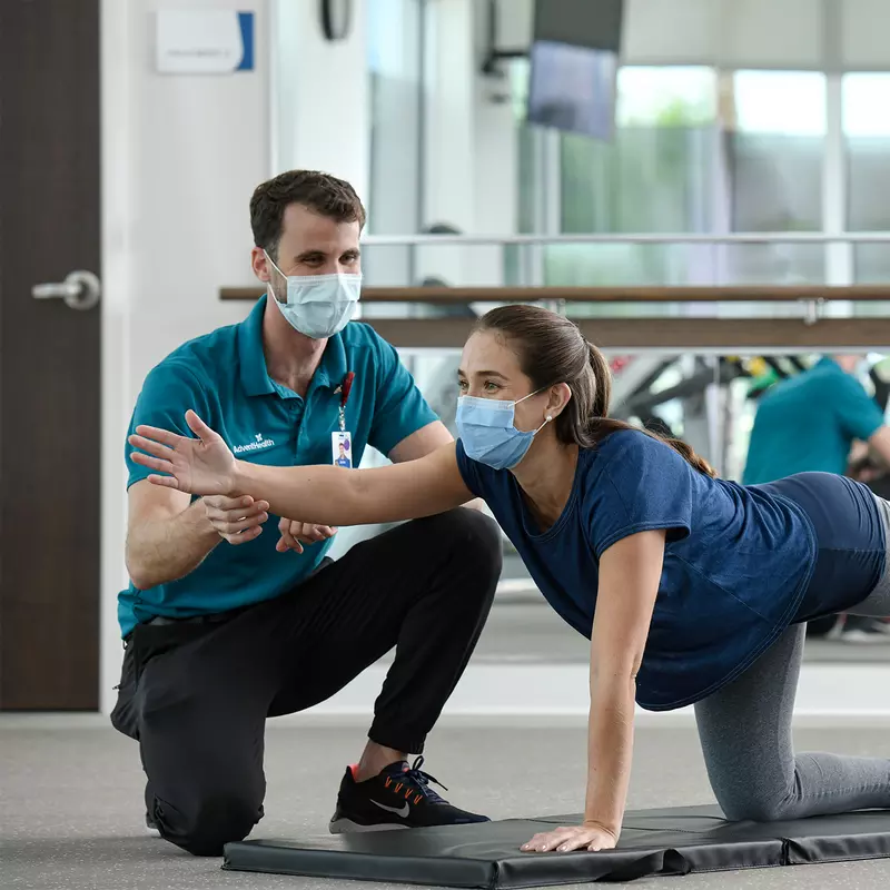 Woman doing an exercise with trainer at the AdventHealth Health Park gym.
