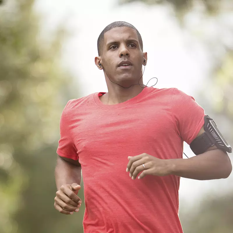 A young man listens to headphones while jogging outdoors