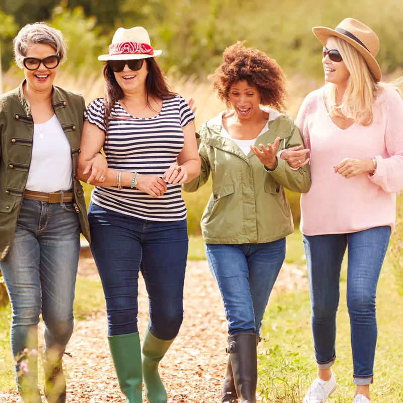 A Group of Inspiring Women Walk Through a Garden Smiling and Laughing