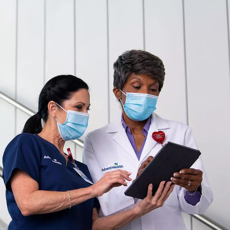 A AdventHealth nurse and physician in a discussion while holding a tablet.