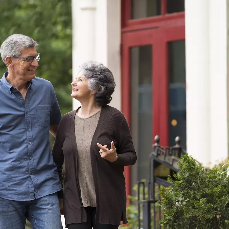 A senior man and woman walking outside of a building.