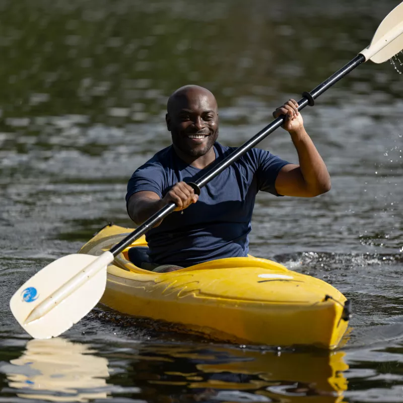 A Smiling Man Kayaks Down a River