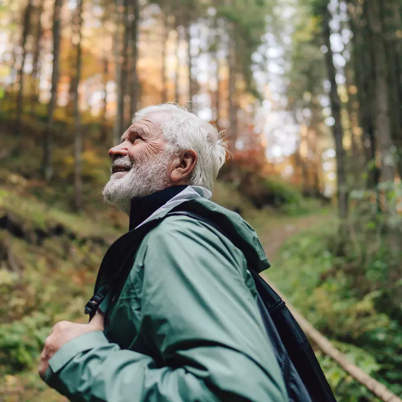 Older man hiking through the forest.