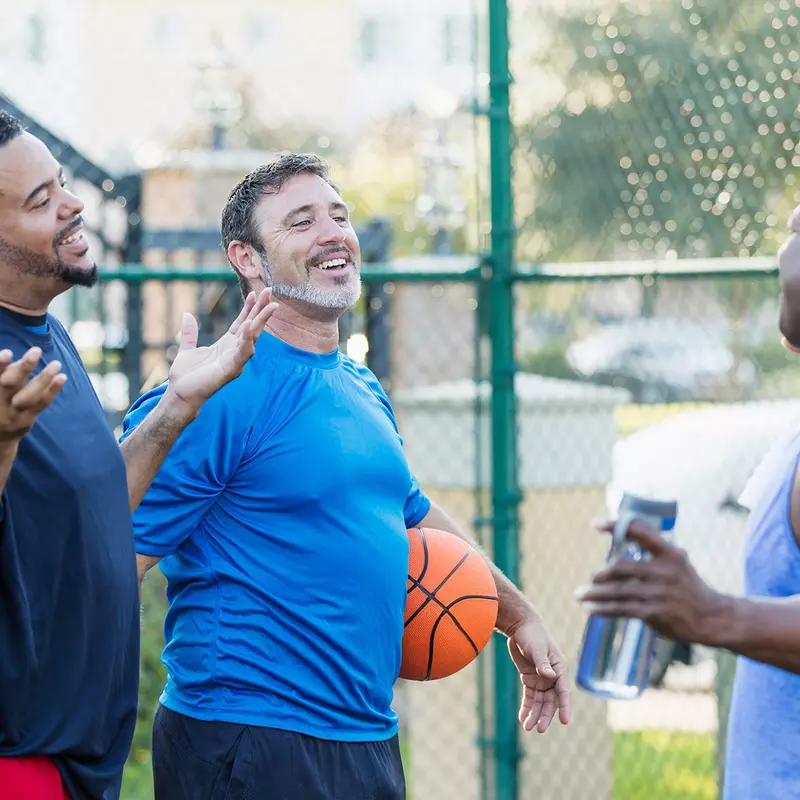 A group of older men talking and taking a break after a round of basketball
